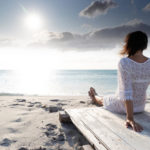 femme assise sur le sable qui regarde l'horizon